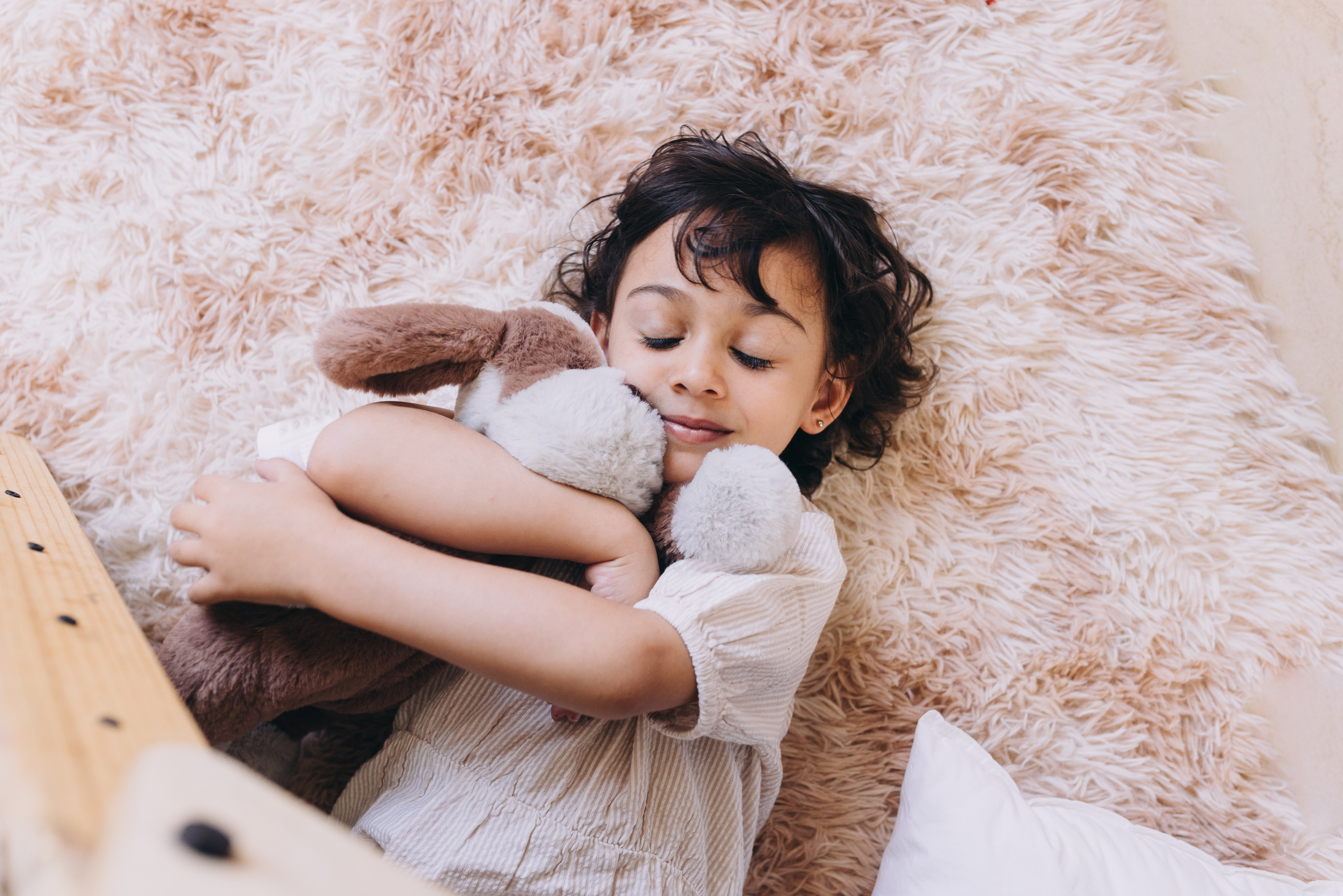 Child Hugging Stuffed Toy in Room