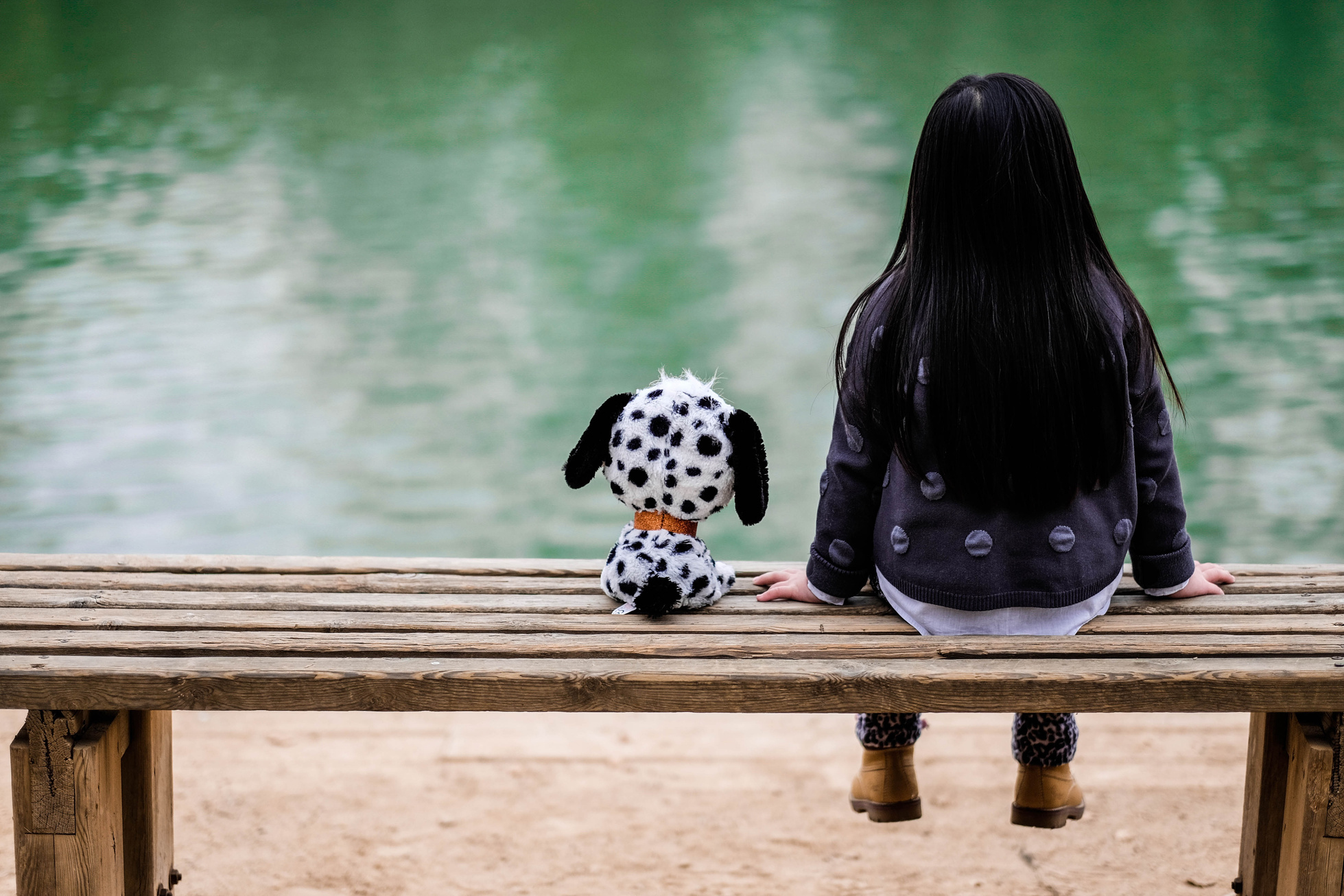 Kid Sitting on a Bench with a Dog Plushie